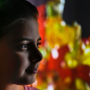 Close-up portrait of young girl looking away against colorful background