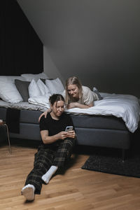 Homosexual female couple sitting on bed and looking at cell phone