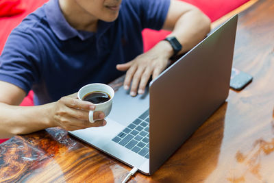 Midsection of woman using laptop on table