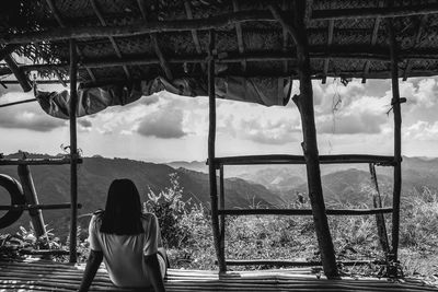 Rear view of woman looking through window