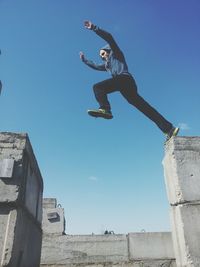 Low angle view of woman standing against blue sky