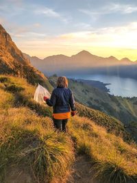 Rear view of man standing on mountains against sky