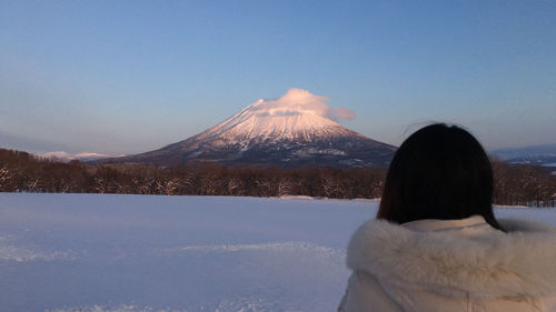 Rear view of woman looking at snowcapped mountain against sky
