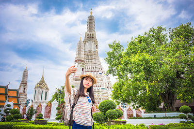 Young woman taking selfie while standing by temple against sky