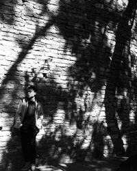 Full length of man standing against wall with shadow