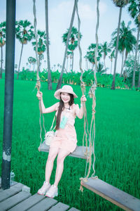 Full length of young woman holding umbrella on field