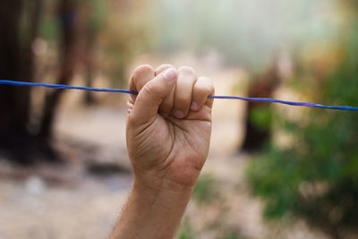 Cropped hand of man holding clothesline