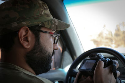 Man holding camera while sitting in car