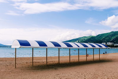 Deck chairs on beach against sky