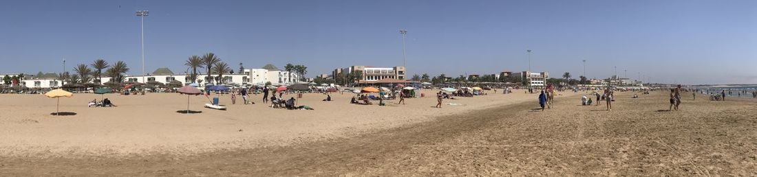 People on beach against sky in city