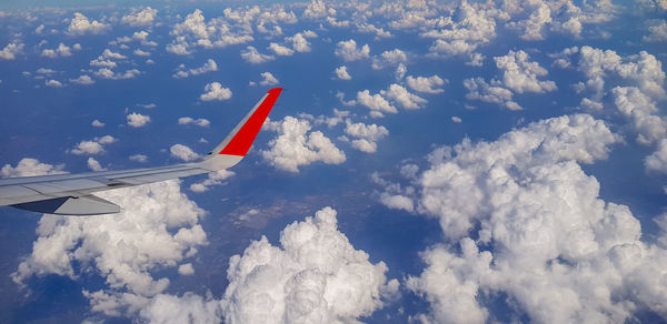 Airplane flying over clouds against sky