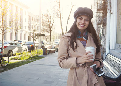 Portrait of young woman standing on street in city