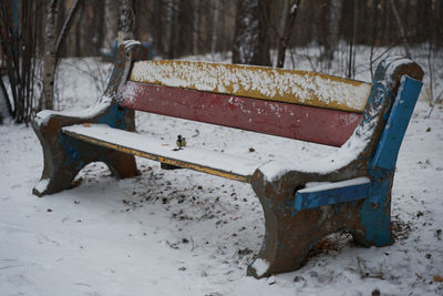 Empty bench on snow covered field during winter