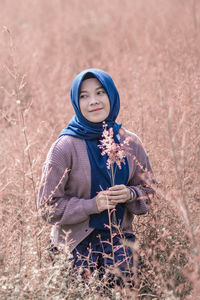 Portrait of smiling young woman standing on field