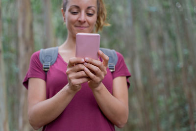 Woman using mobile phone while standing in forest