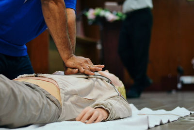 Midsection of man performing cpr on dummy 