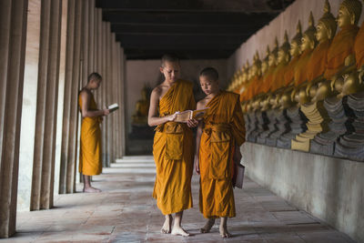 Monks reading book while walking in corridor