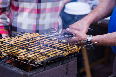 Cropped image of man grilling chicken at market stall