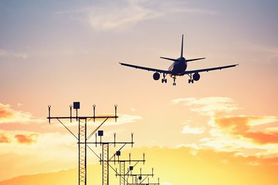 Low angle view of silhouette airplane against sky during sunset