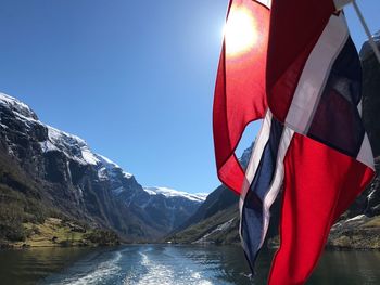 Red flag by mountain against clear sky