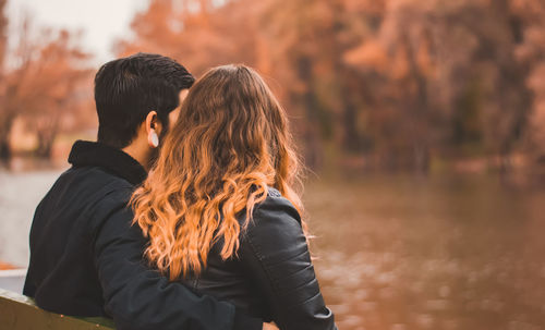 Young couple relaxing in a river bank in autumn