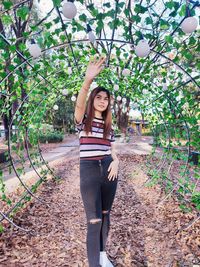 Portrait of young woman standing amidst plants