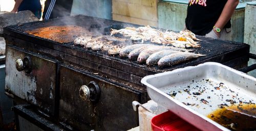 Midsection of man grilling fish on barbecue grill