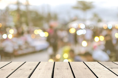 Boardwalk against illuminated lights at night