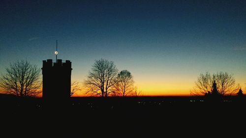 Silhouette of bare trees against clear sky