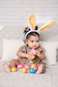 High angle view of cute baby girl sitting on sofa at home