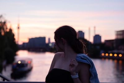 Thoughtful woman standing against river during sunset