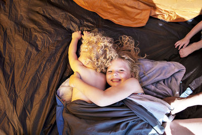 High angle view of siblings resting in sleeping bag at tent