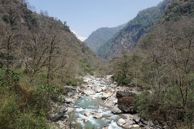 Scenic view of stream by mountains against sky