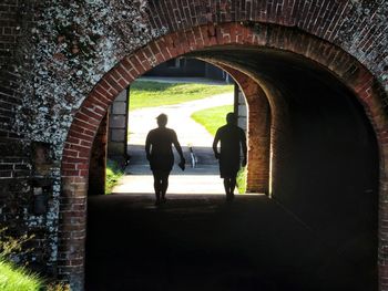 Rear view of people walking in tunnel