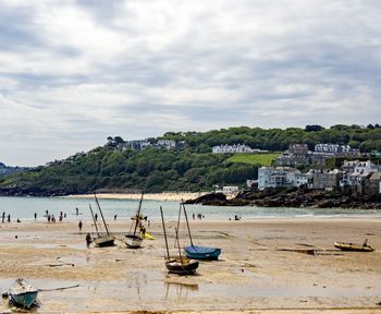 Boats moored on beach by sea against sky