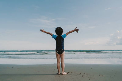 Full length rear view of boy standing at beach