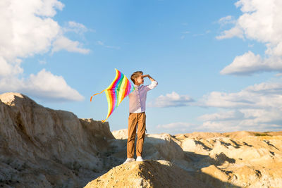 Full length of woman standing on rock against sky