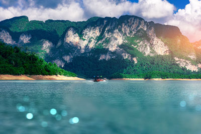 Tourists take a boat to see the beauty of the limestone mountains in the ratchaprapa dam in thailand