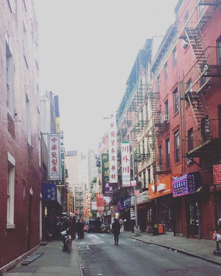 PEOPLE WALKING ON ROAD AMIDST BUILDINGS IN CITY