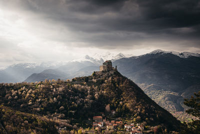 Panoramic view of townscape by mountains against sky