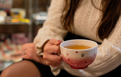 Midsection of woman holding coffee cup