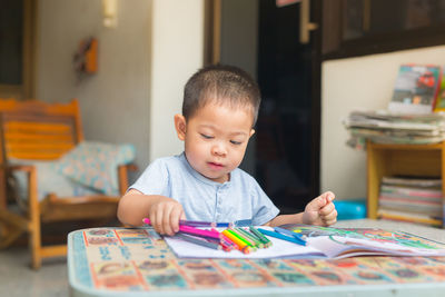 Close-up of cute boy sitting on table at home