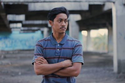 Man looking away while standing with arms crossed