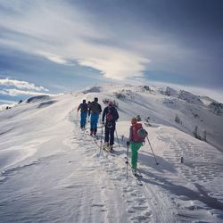 Rear view of people on snowcapped mountain against sky