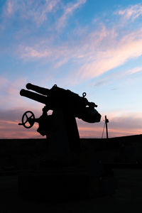 Silhouette weapon against sky during sunset