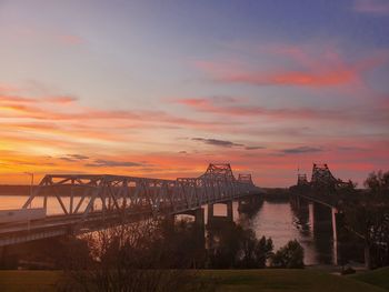 Bridge over river against cloudy sky during sunset