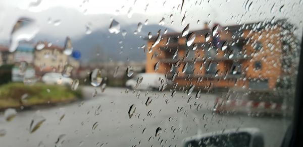 Close-up of waterdrops on glass against window during rainy season