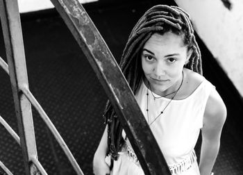 Portrait of woman with dreadlocks standing by railing