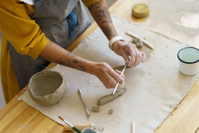 Woman ceramist make pottery cup in studio. creative girl pottery master with tattoo shaping pot mug