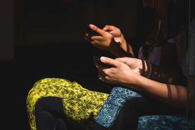 Midsection of friends using mobile phone at home